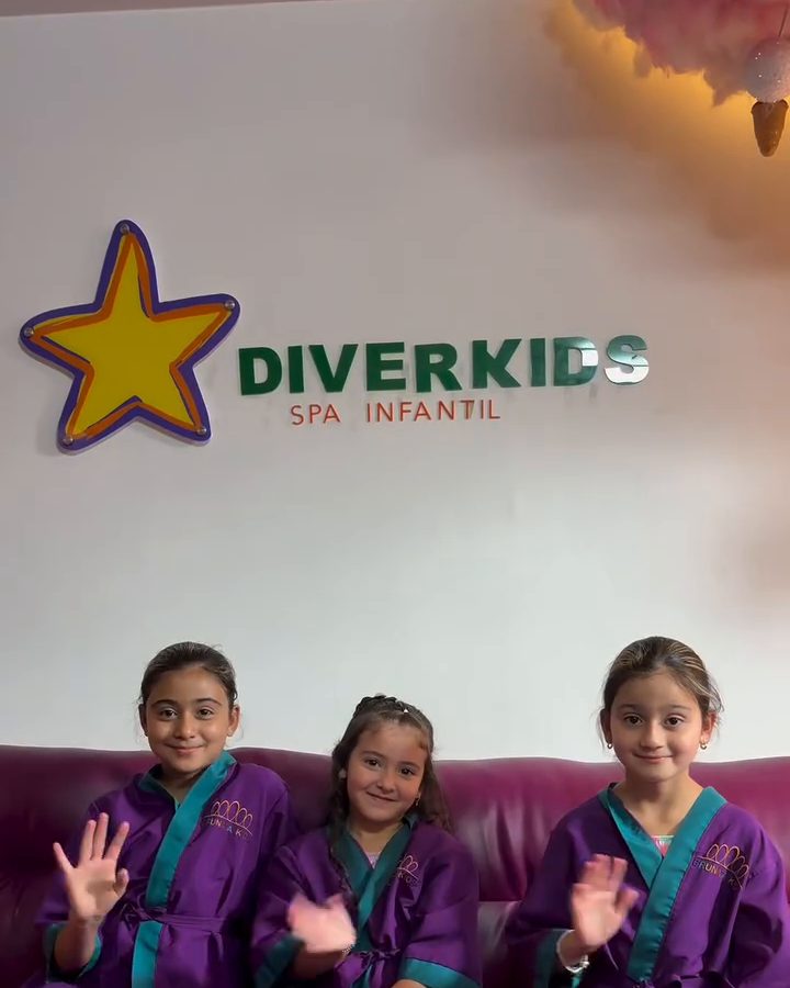 Tres niñas en bata morada saludan bajo el logo de Diverkids Spa Infantil