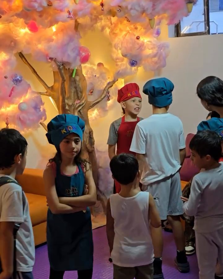 Niños con gorro de chef junto al árbol de luces de la sala de bienvenida de Diverkids